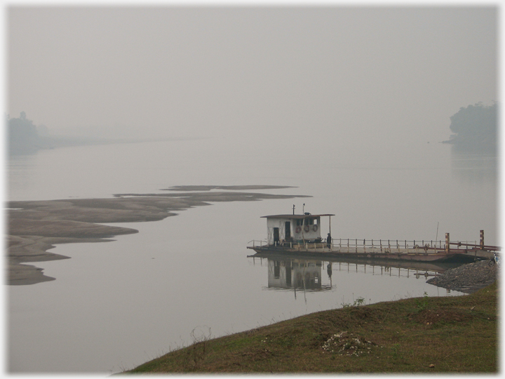 Ferry at bank with river beyond disappearing into mist.