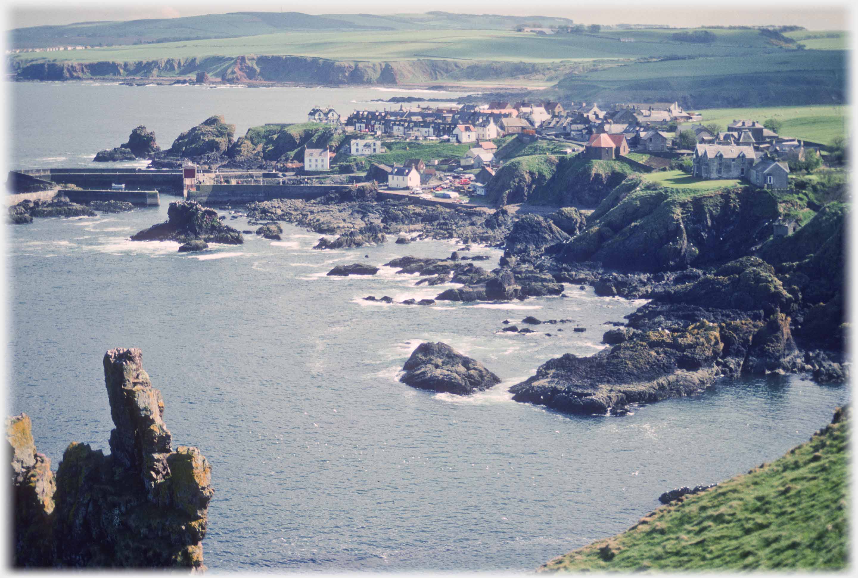 Looking down into a bay with village, rocks and harbour.