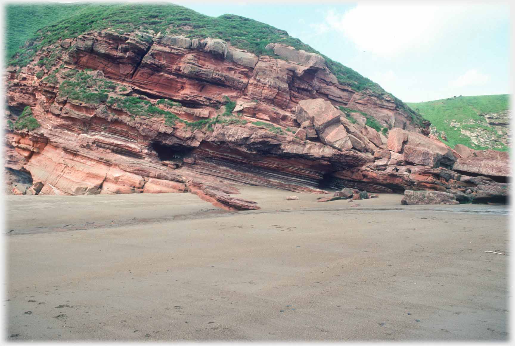 Complex of rocks between grass and sea.