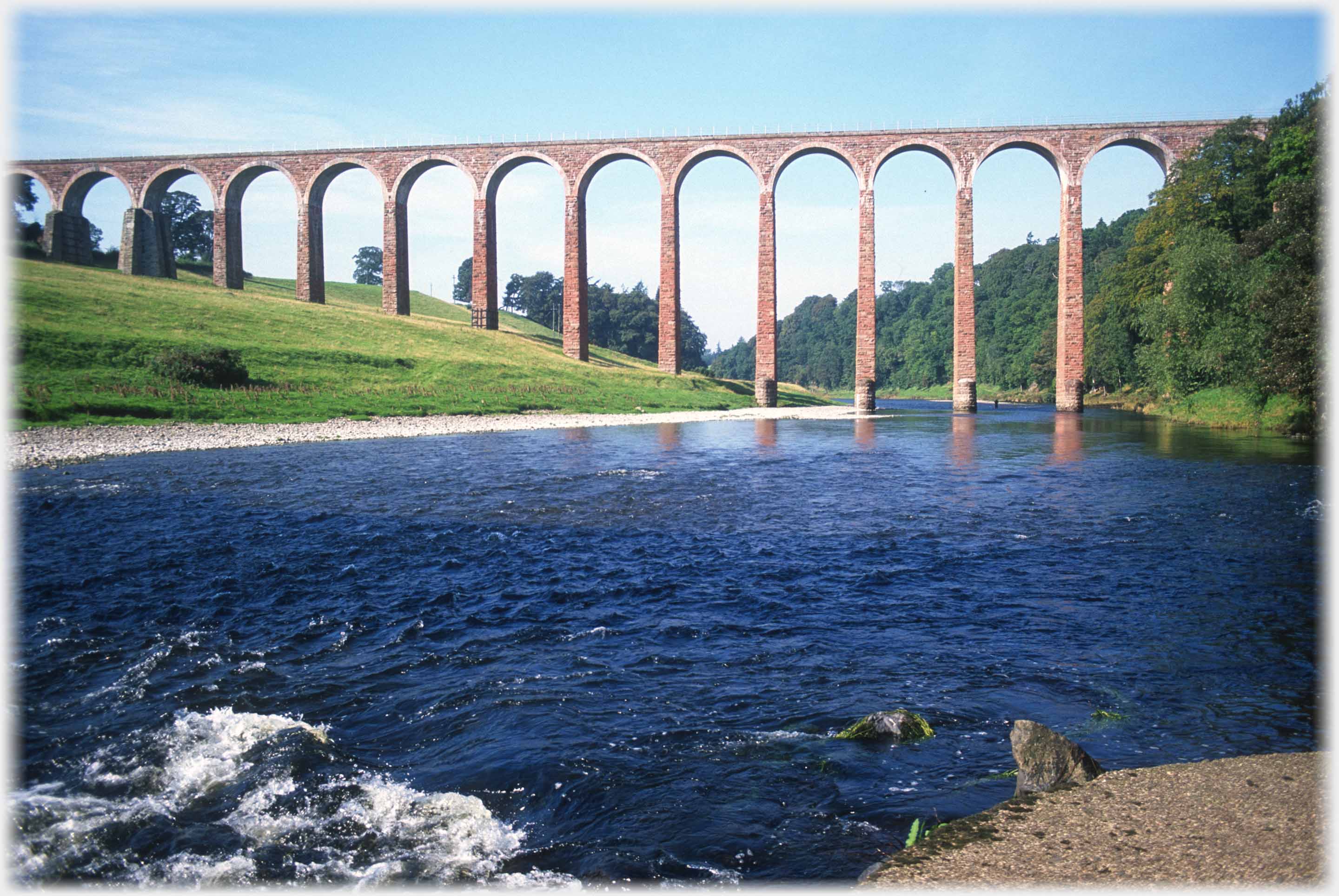 Viaduct viewed from beside a river.