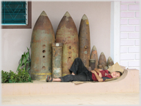 Woman sleeping on the ground by a line of bombs.