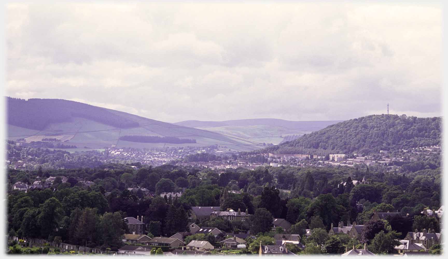 Wide valley with trees in front and town beyond.