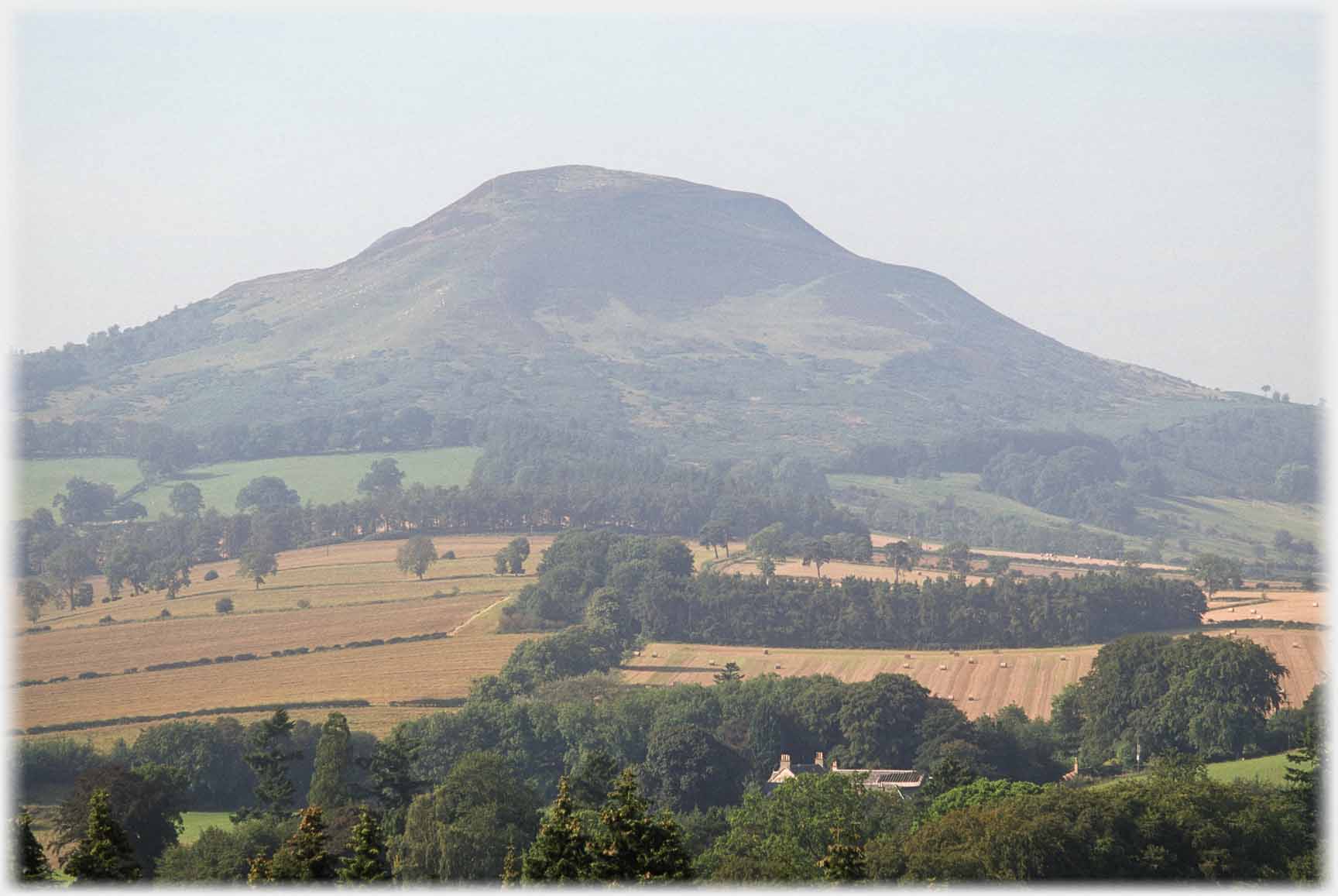 Slightly misted hill with fields in foreground.