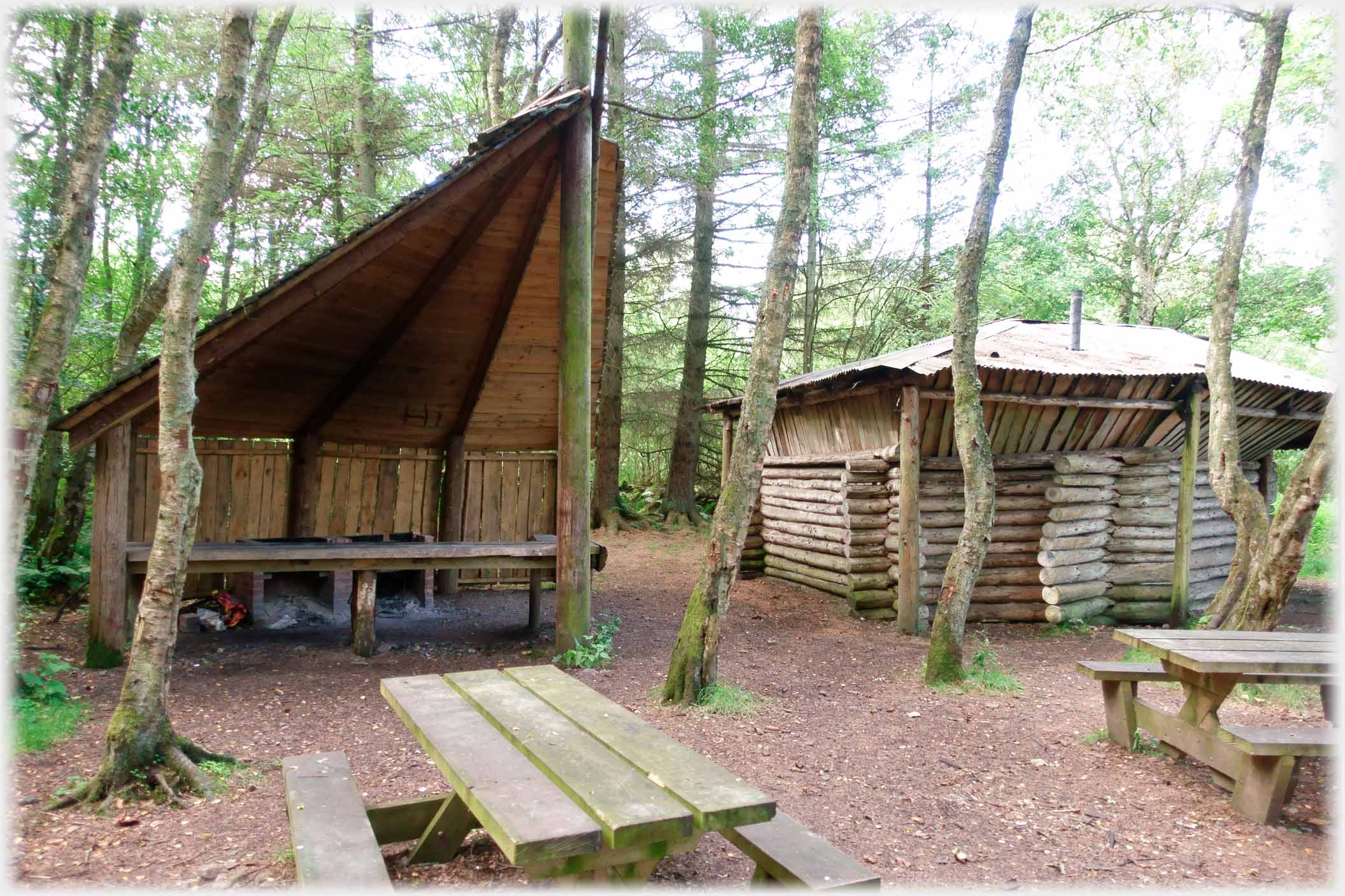 Two wooden buildings with benches and tables in front.