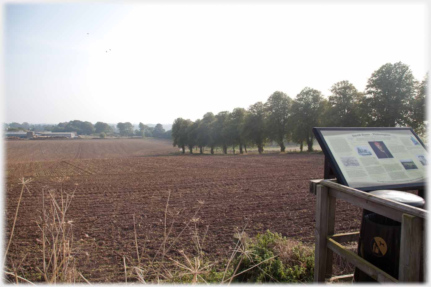 Information plaque overlooking field with line of trees.