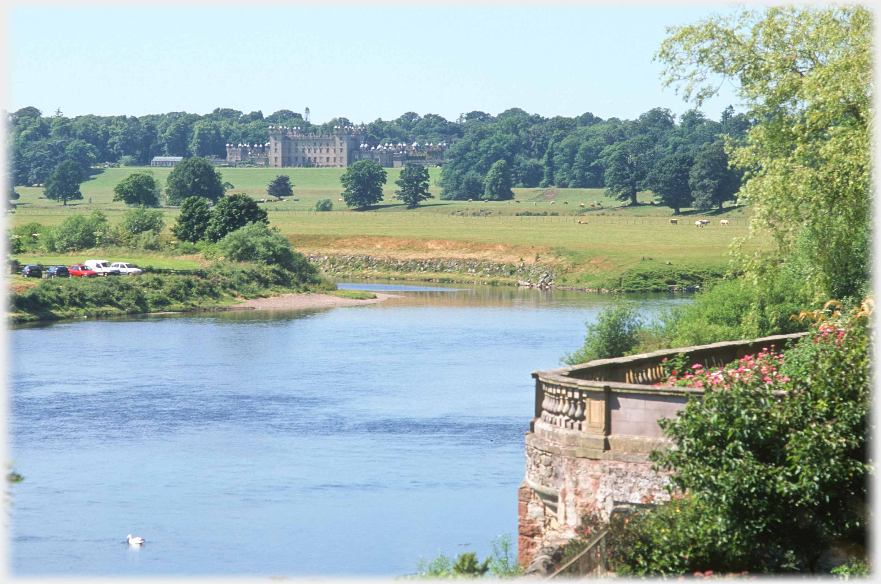 Balustraded  terrace overlooking river with large castle in distance.