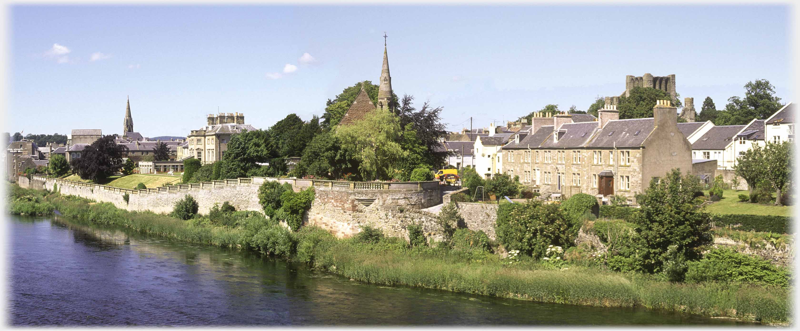 Two church spires with house between across river.