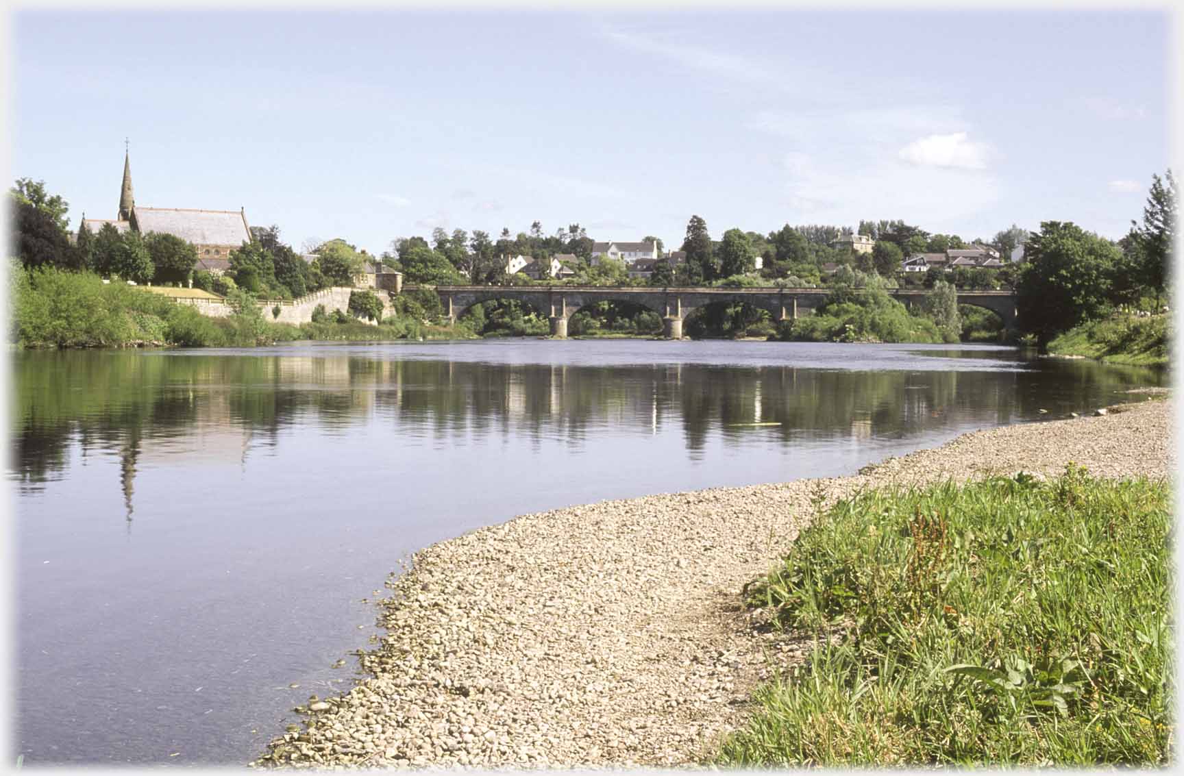 Bridge and church reflected in river.