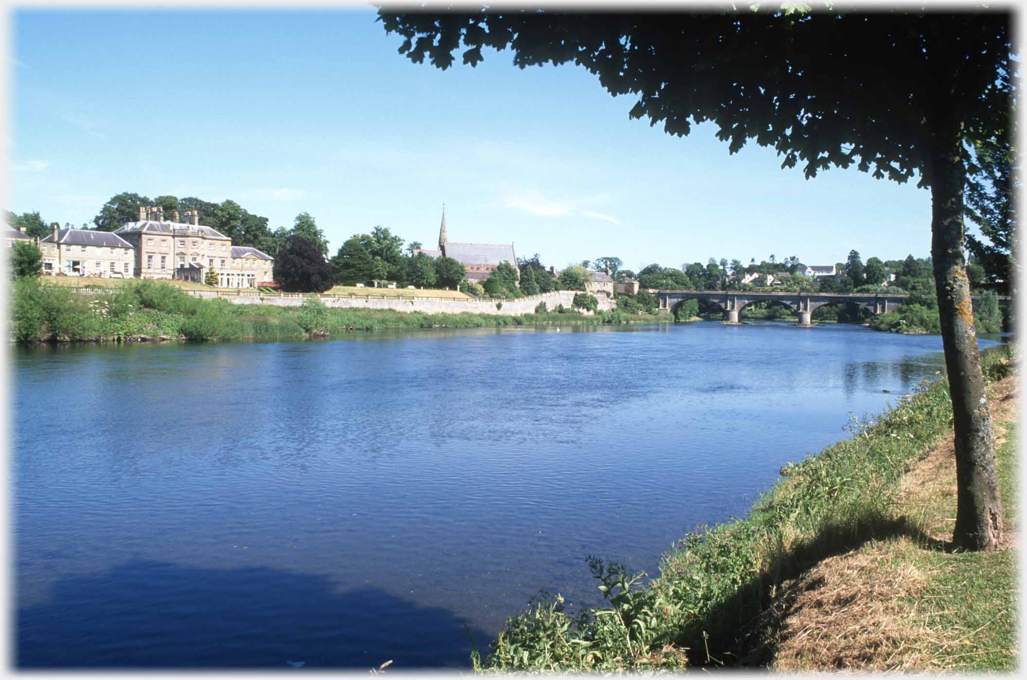 River with karge house and distant bridge.