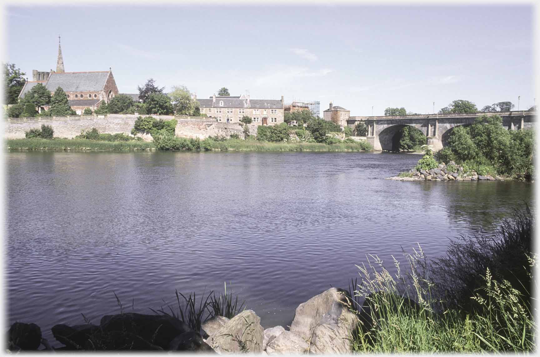 Church and row of houses reflected in river.