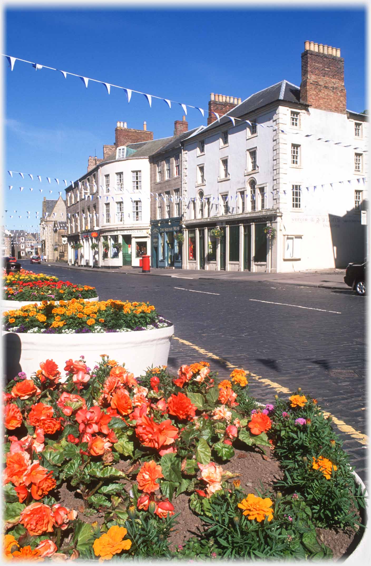 Building across road with floral display on nearside.