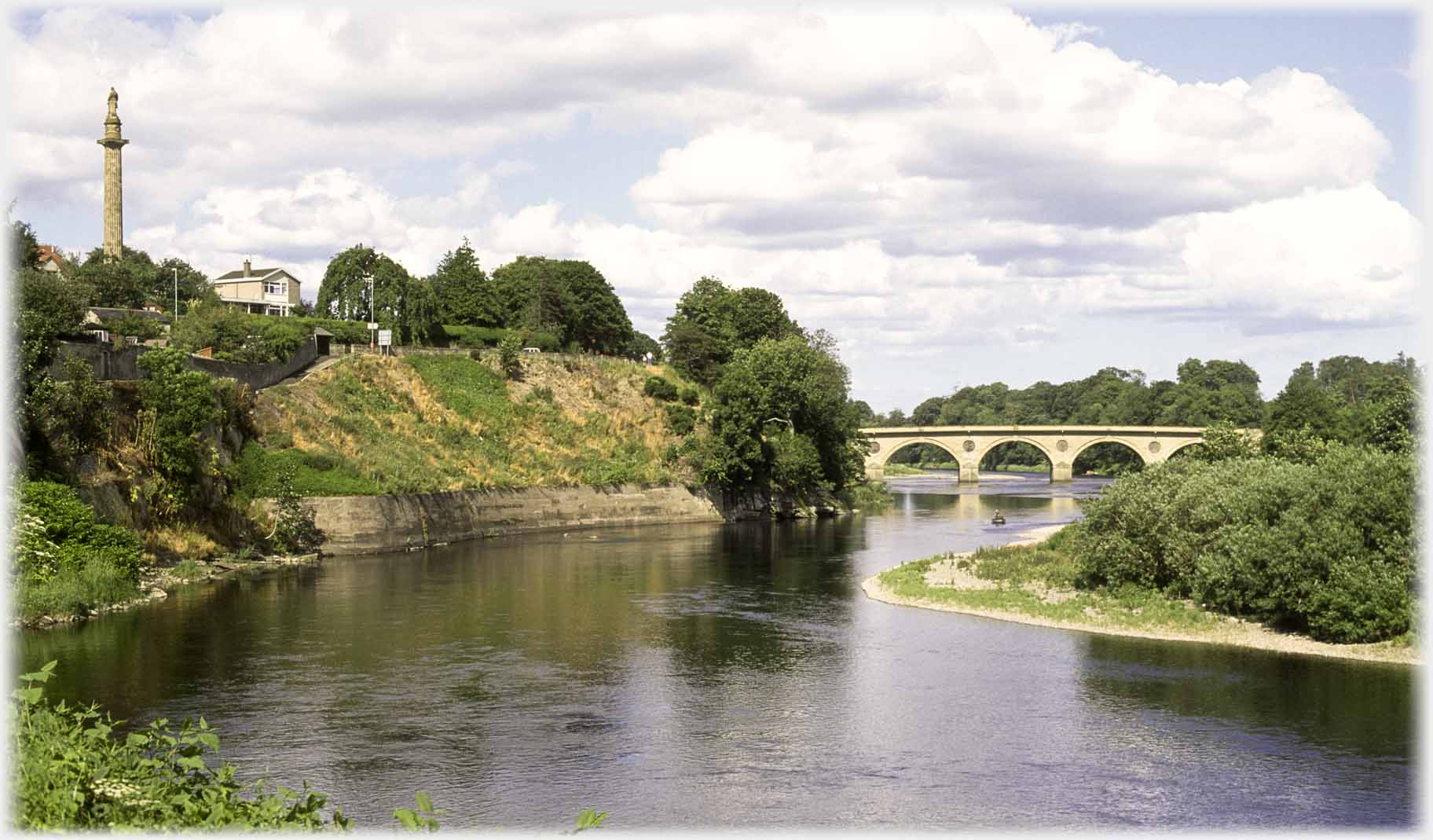 River curving under bridge to right column high on bank on left.