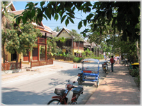 Dappled street with large wooden buildings.