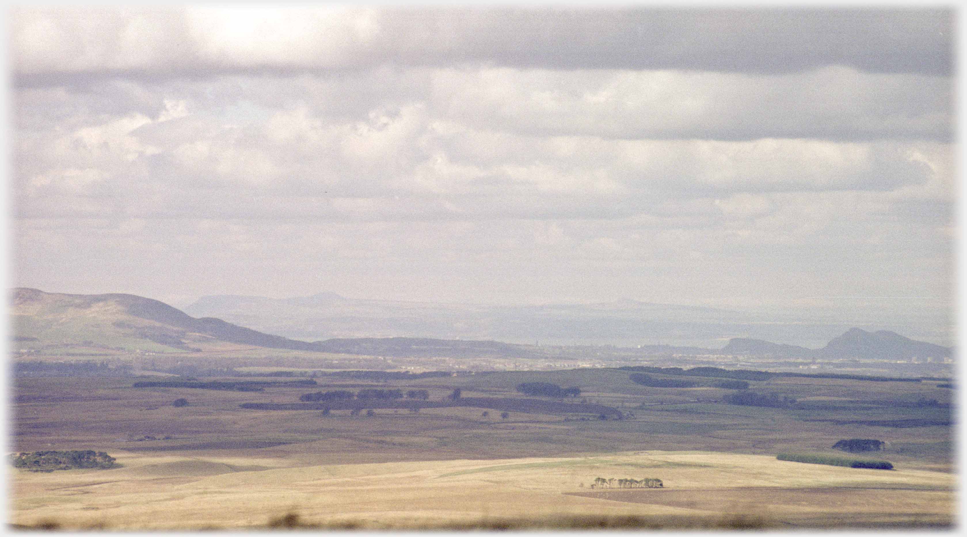 Looking across plane of soft browns to outlines of hills.