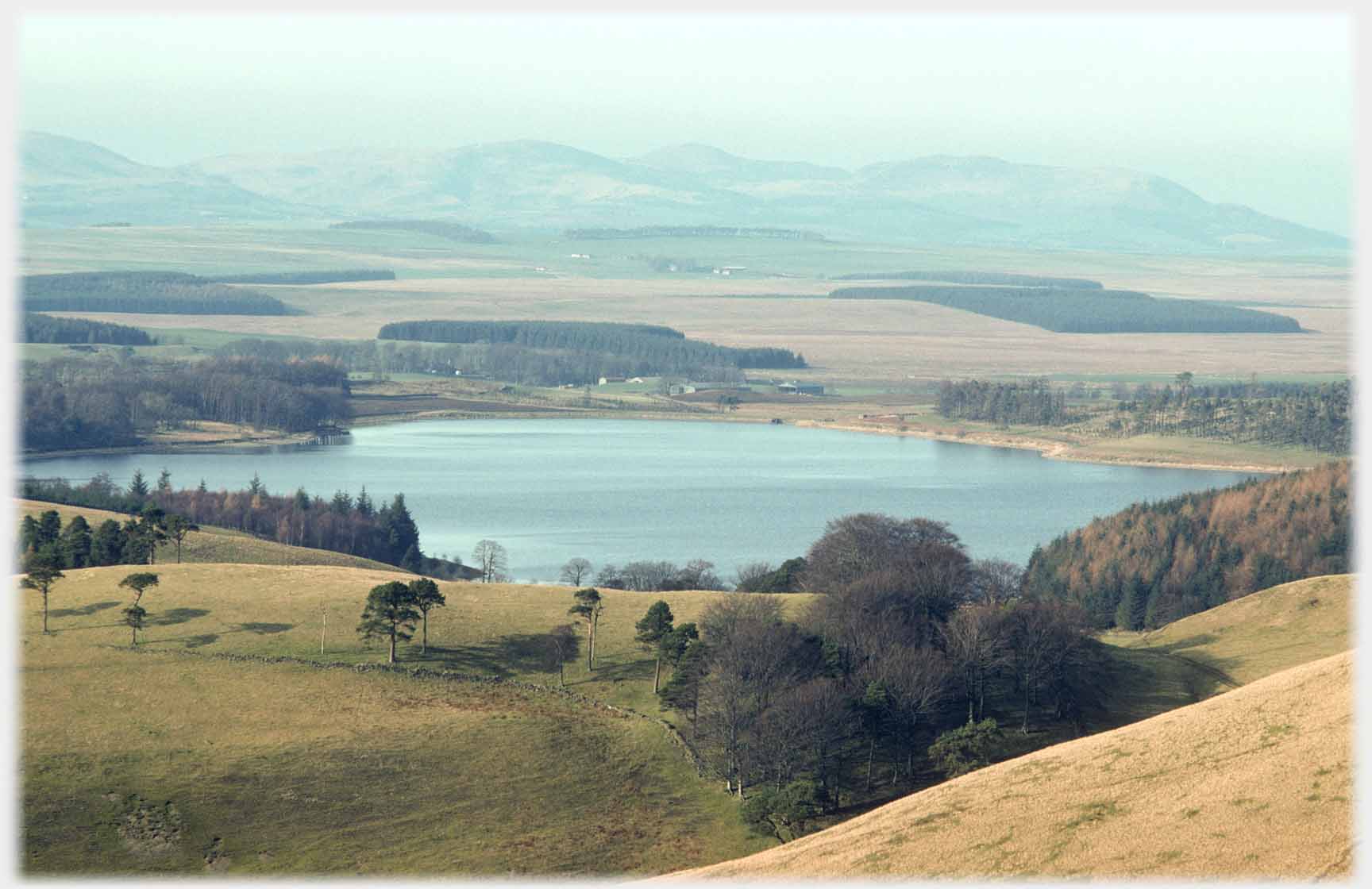 Looking down on small loch, plane and hills beyond.