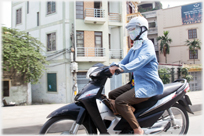 Woman motorcyclist fully covered, apart from hand.