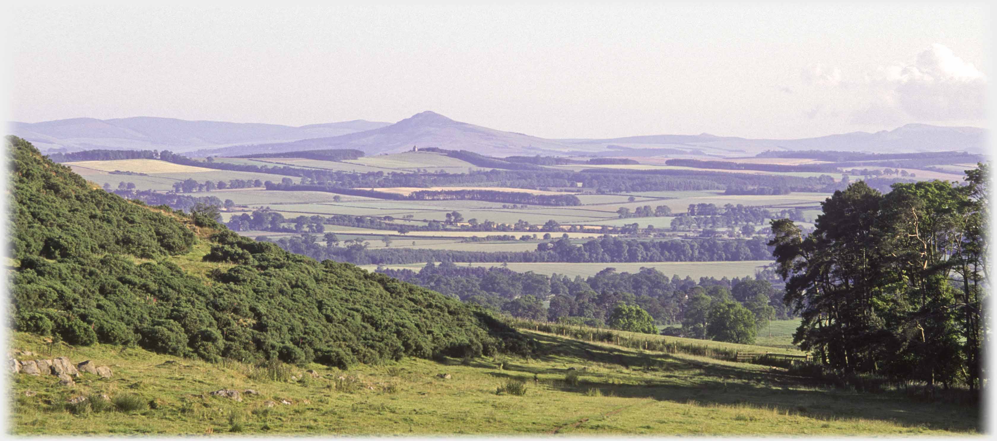 Looking down across a wide plain to volcano shaped hill.