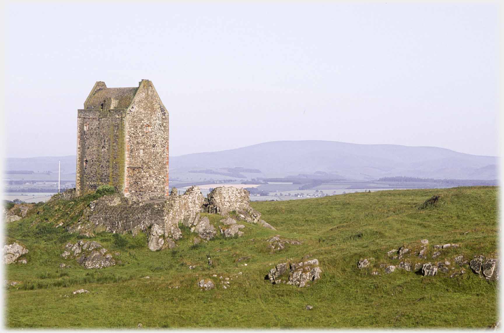 Tower house to left, distant hills.