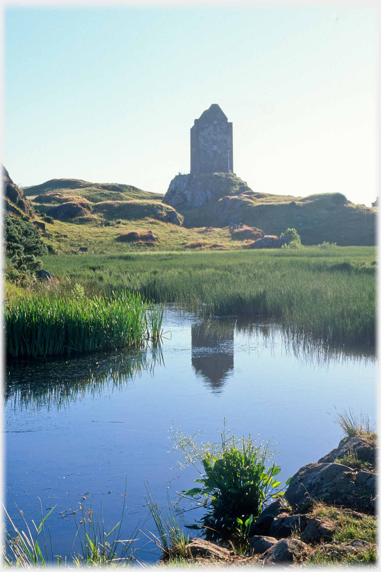 Silhouette of tower hoouse reflected in pool.