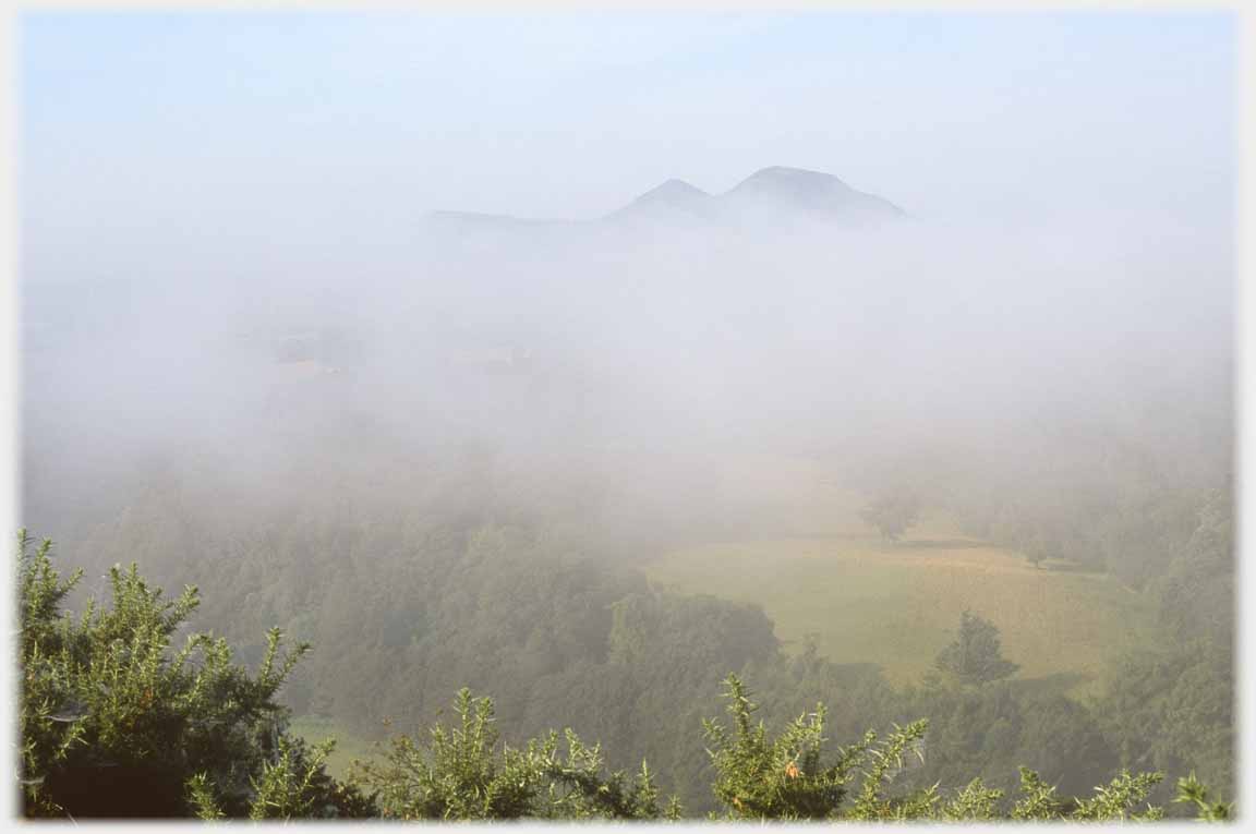 Point of hill and fields visible but cloud covered.