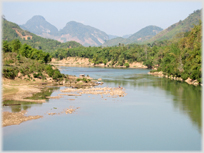 River banked with trees and mountains beyond.