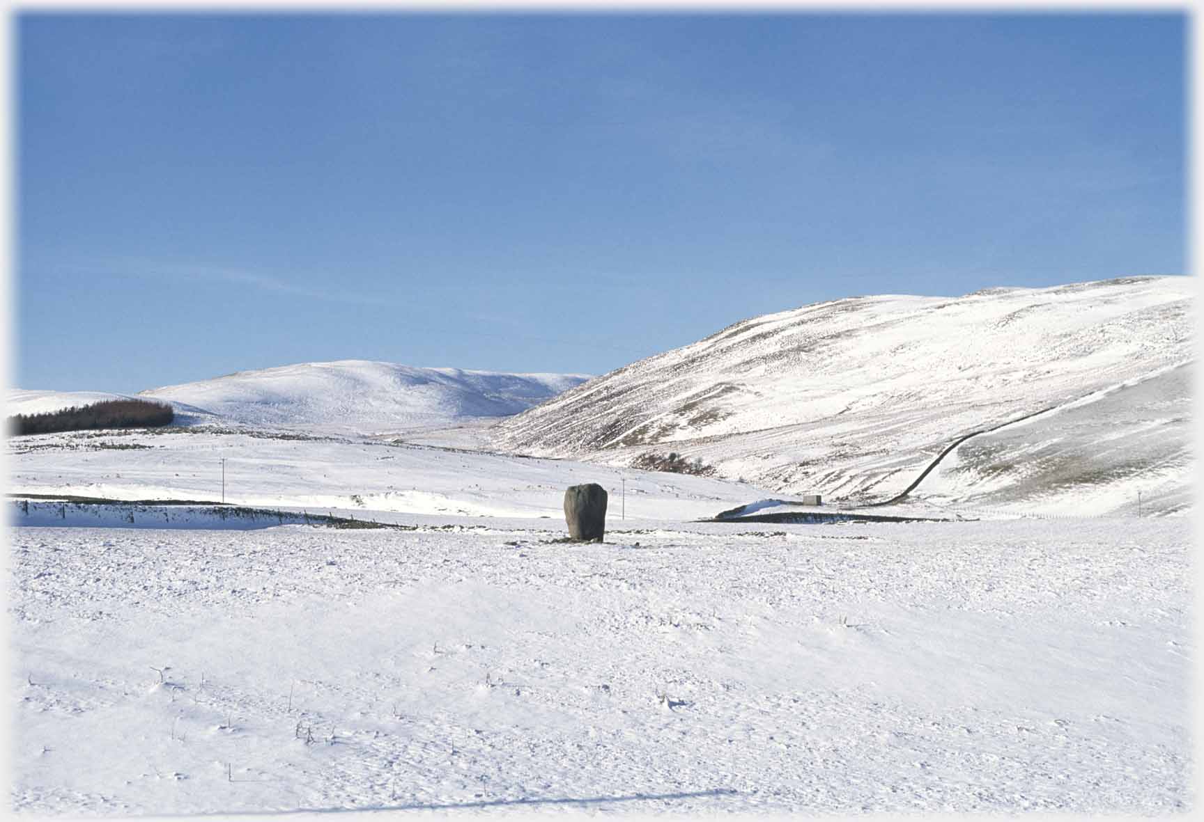 Standing stone in snow covered landscape.