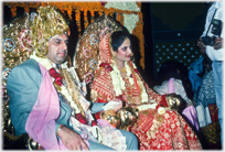 Delhi wedding couple in full regalia on thrones.