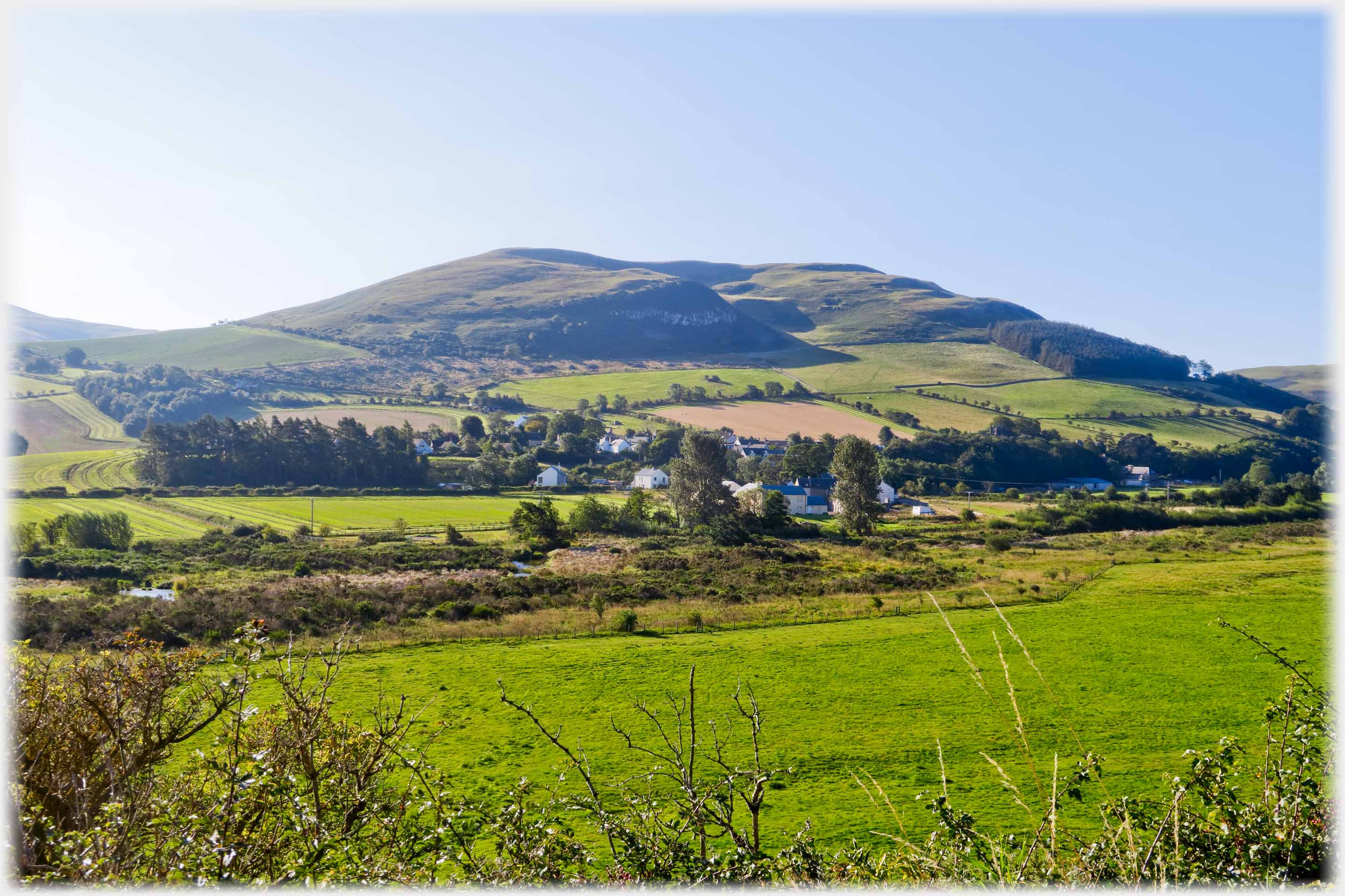 Hill with village in trees at its foot.