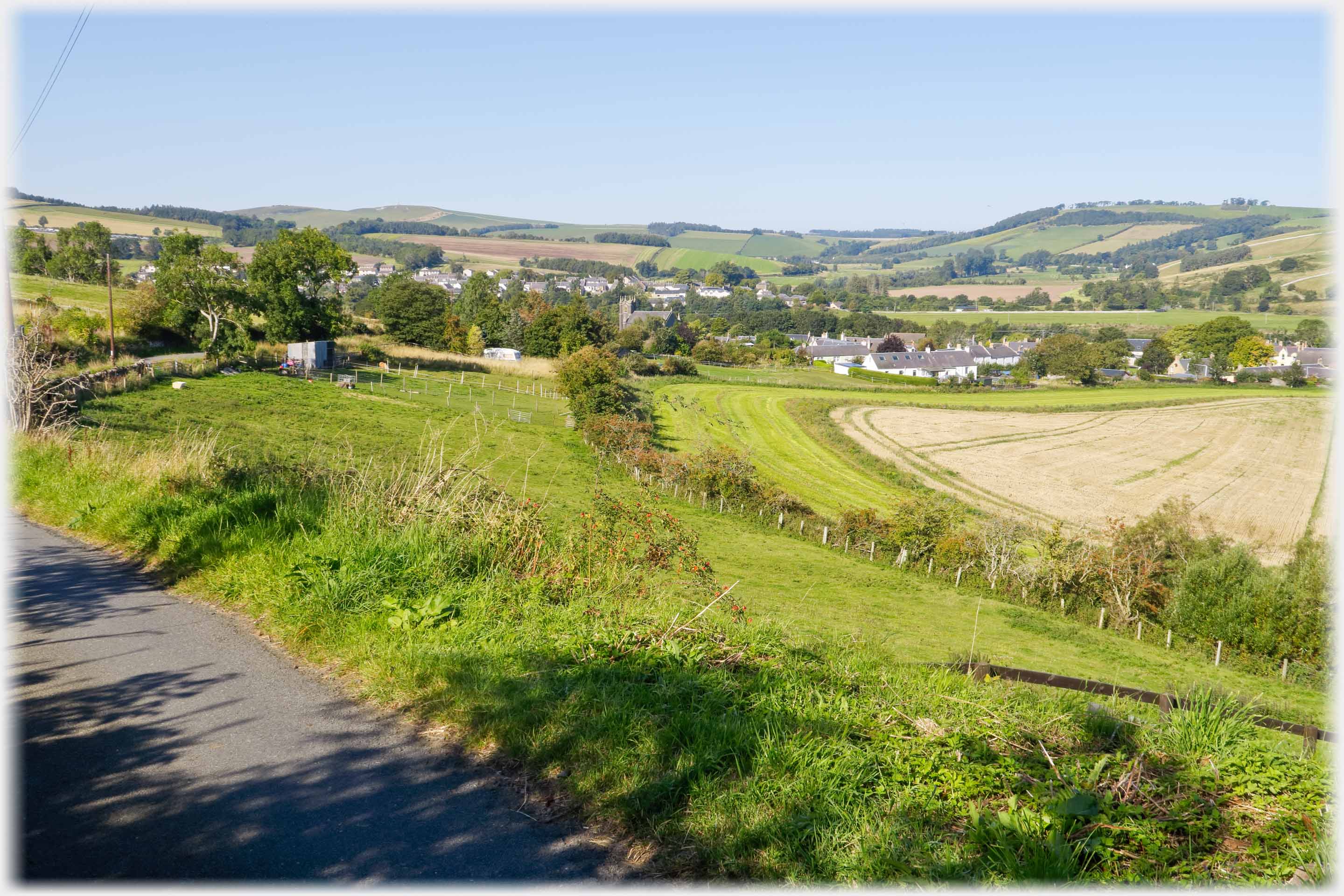 Looking across fields two villages with surrounding low hills.