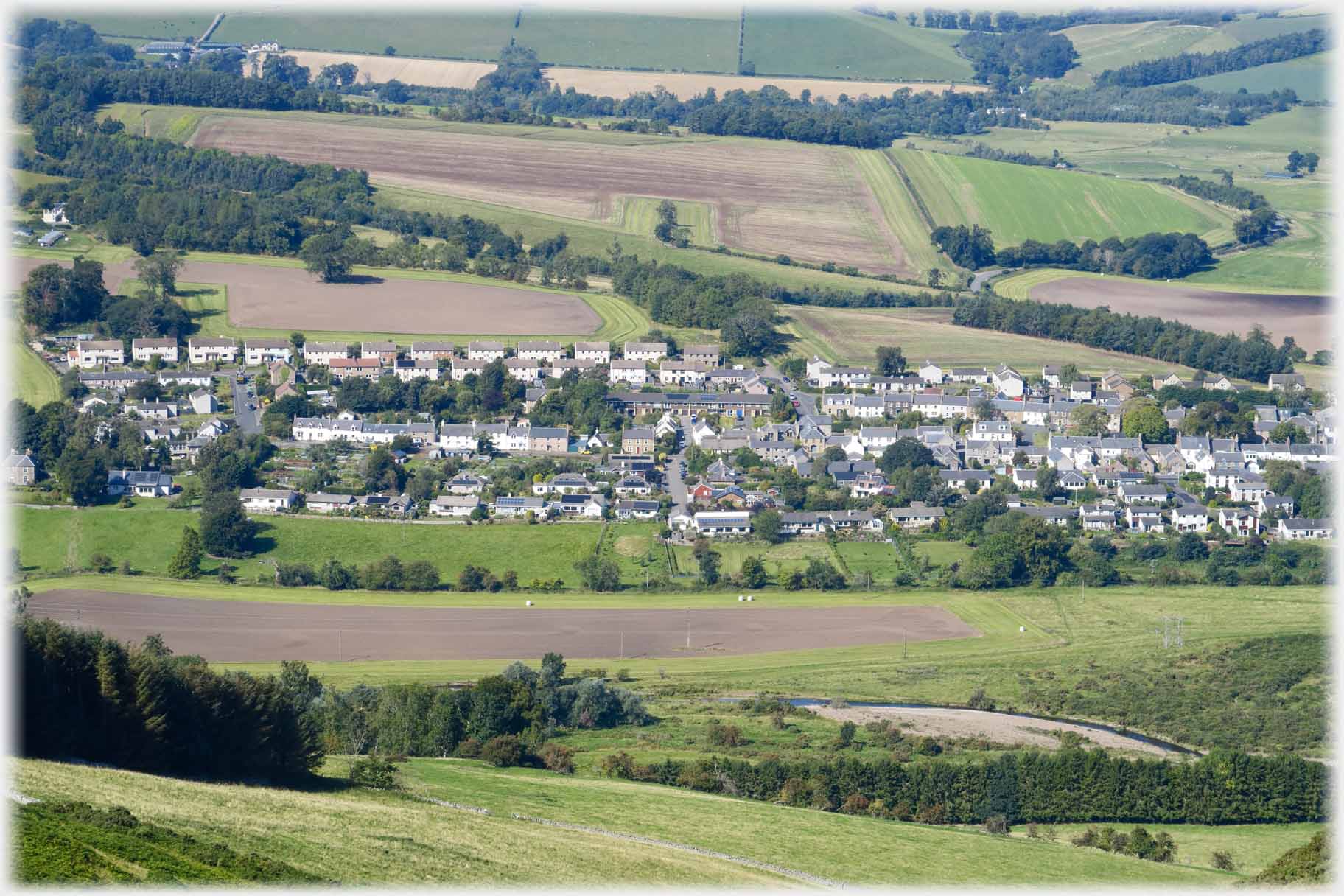 Looking down on packed houses, fields around them.