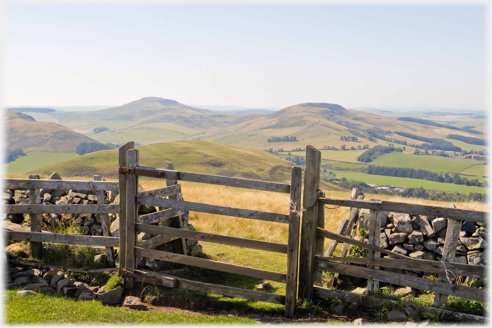 Gate in dyke with two hills beyond.