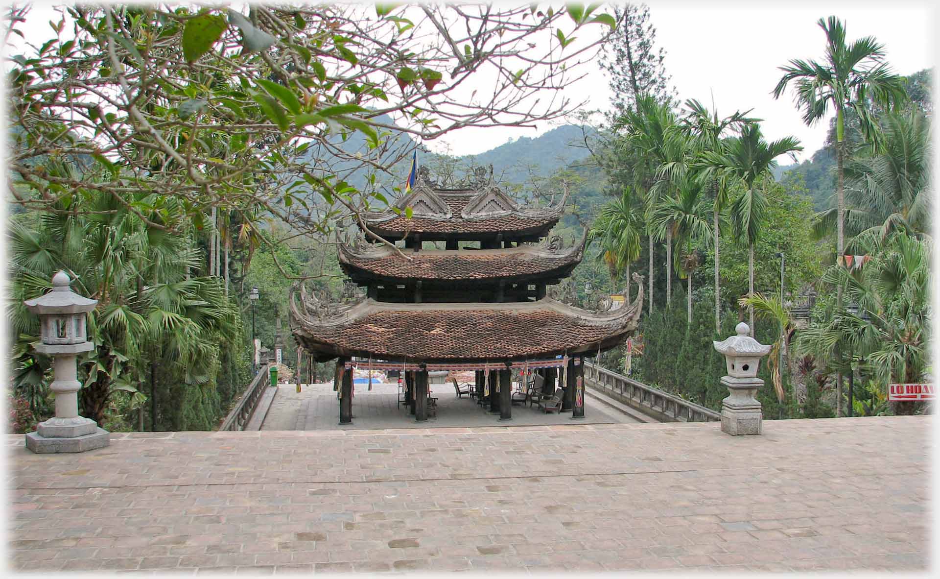 Building with three tiered roof below steps with two lanterns.