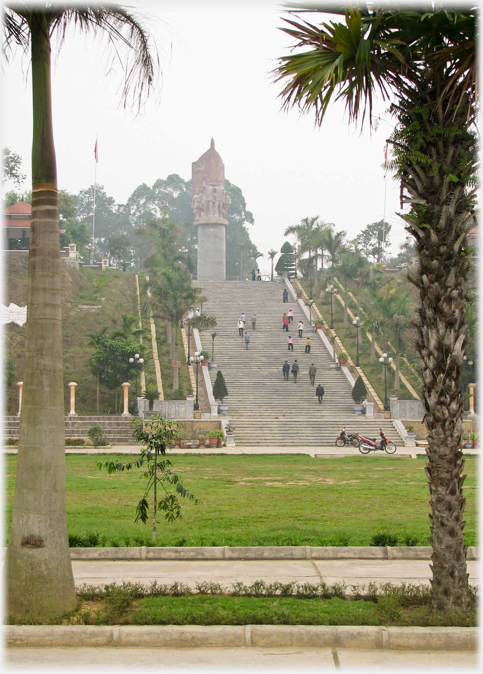 Monumental staircase leading up banking to pillar with statues on top.