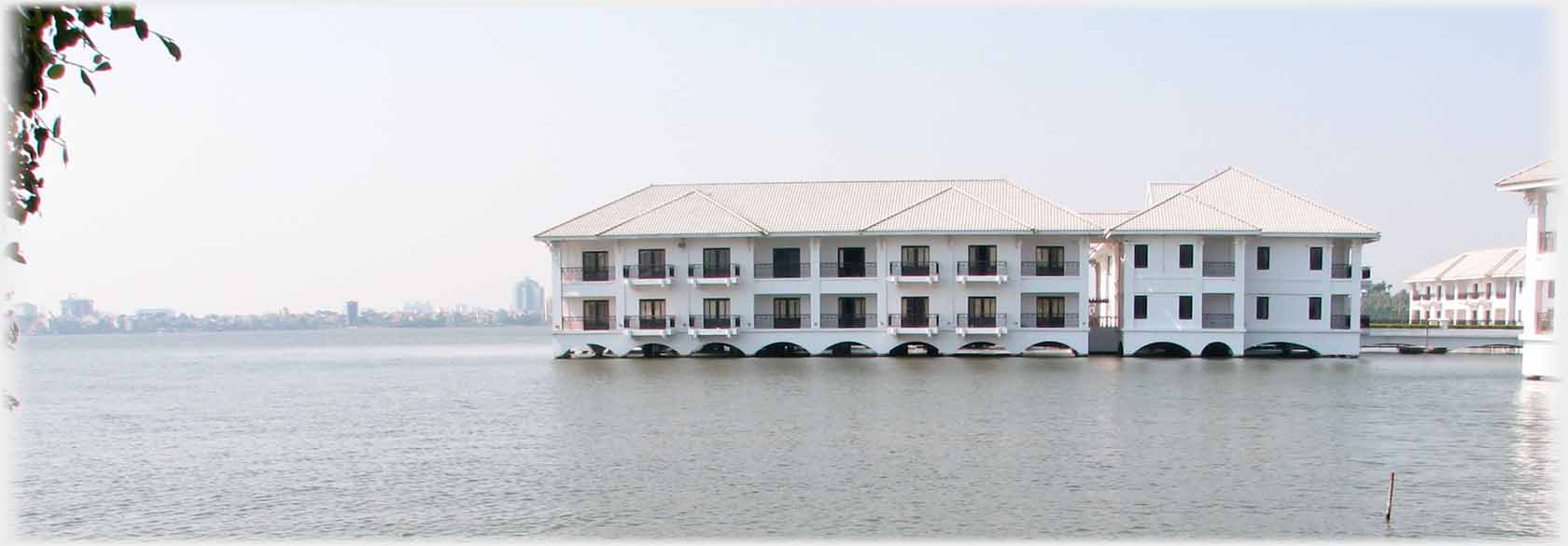 Two storey white building standing in water.