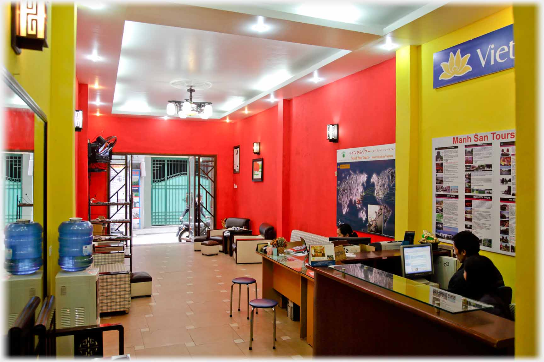 Long modern room to street door, person at desk with computer.