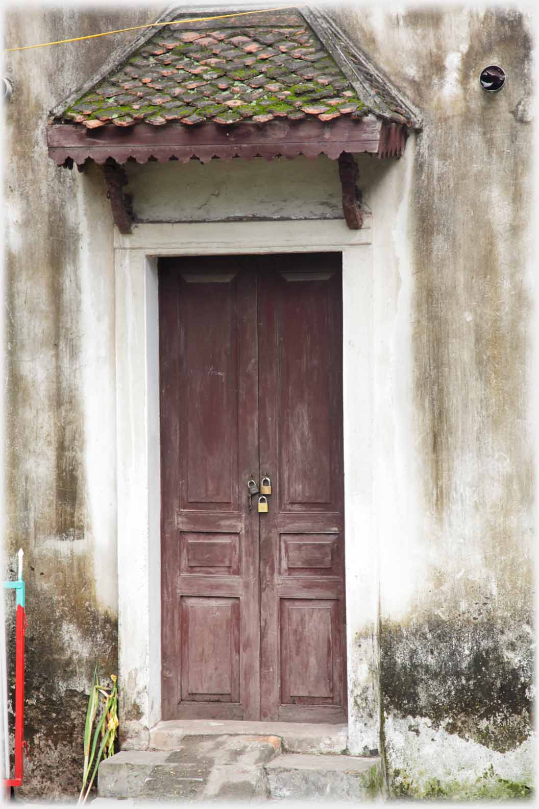 Double door under triangular porch with three padlocks near centre.