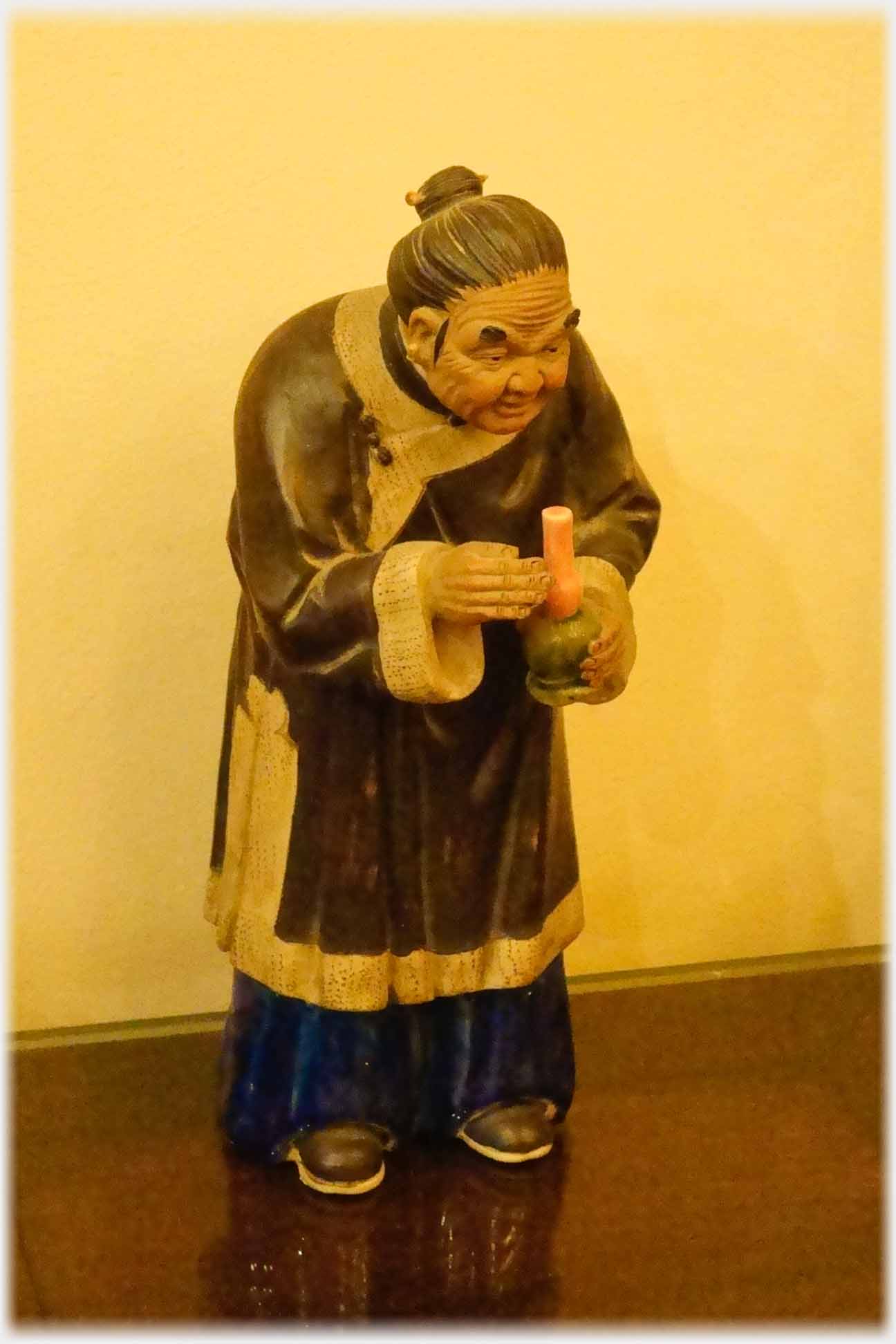 Figure of old person holding candle.