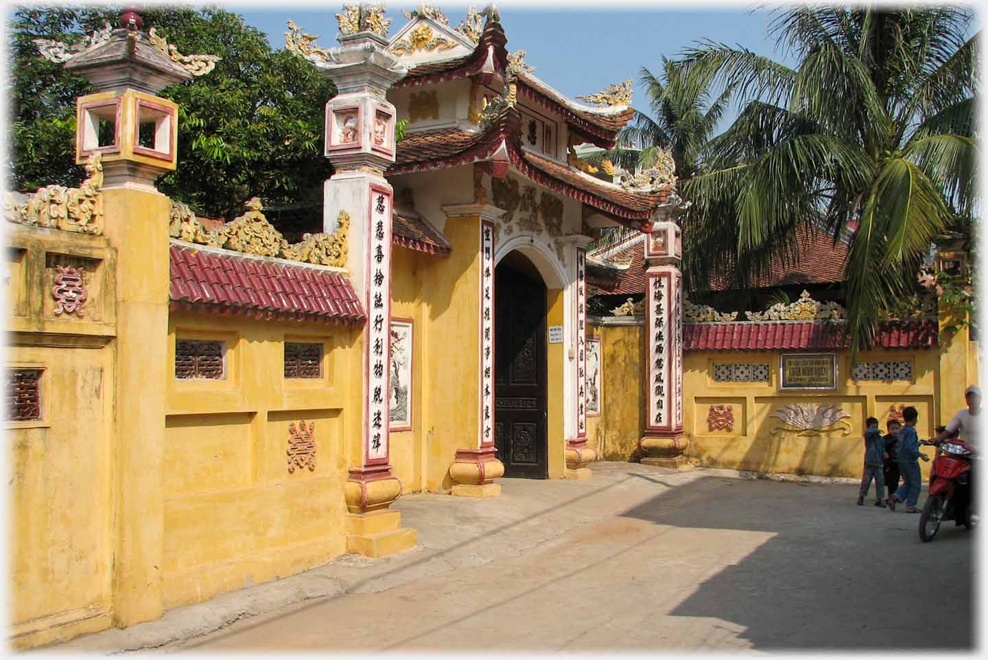 Entrance gate in wall, all painted ochre with Chinese characters on columns.