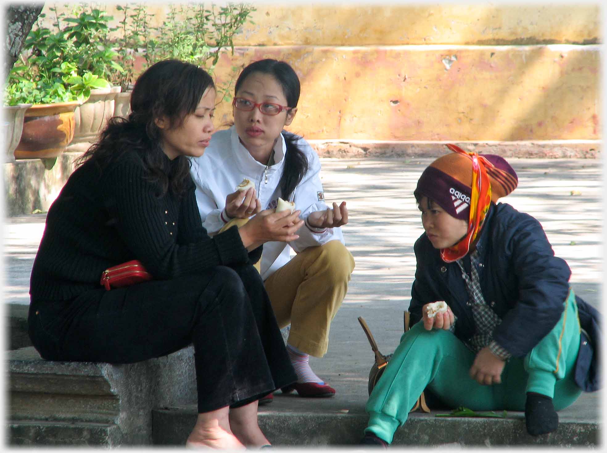 three young people sitting, eating and talking.