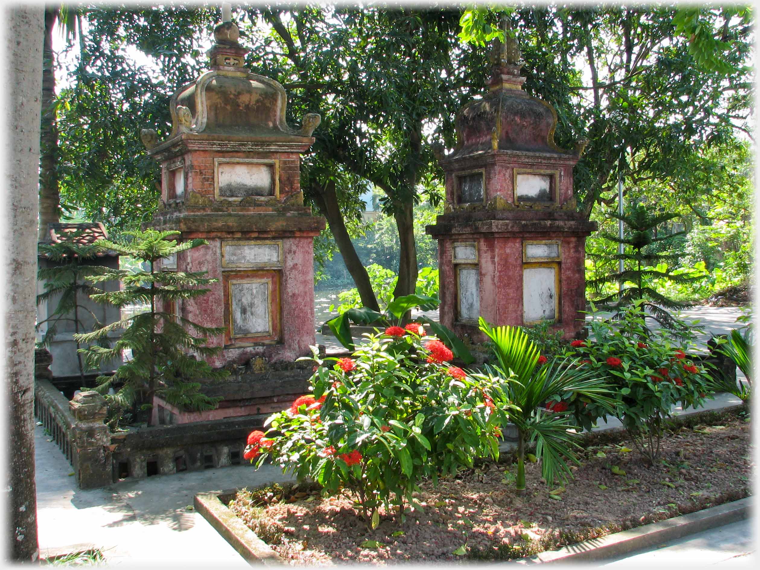 Two stone monuments in garden with trees.