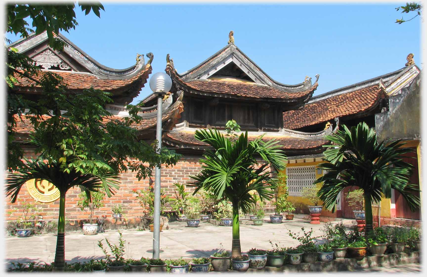 Roofs of building seen over wall, palms in foreground.