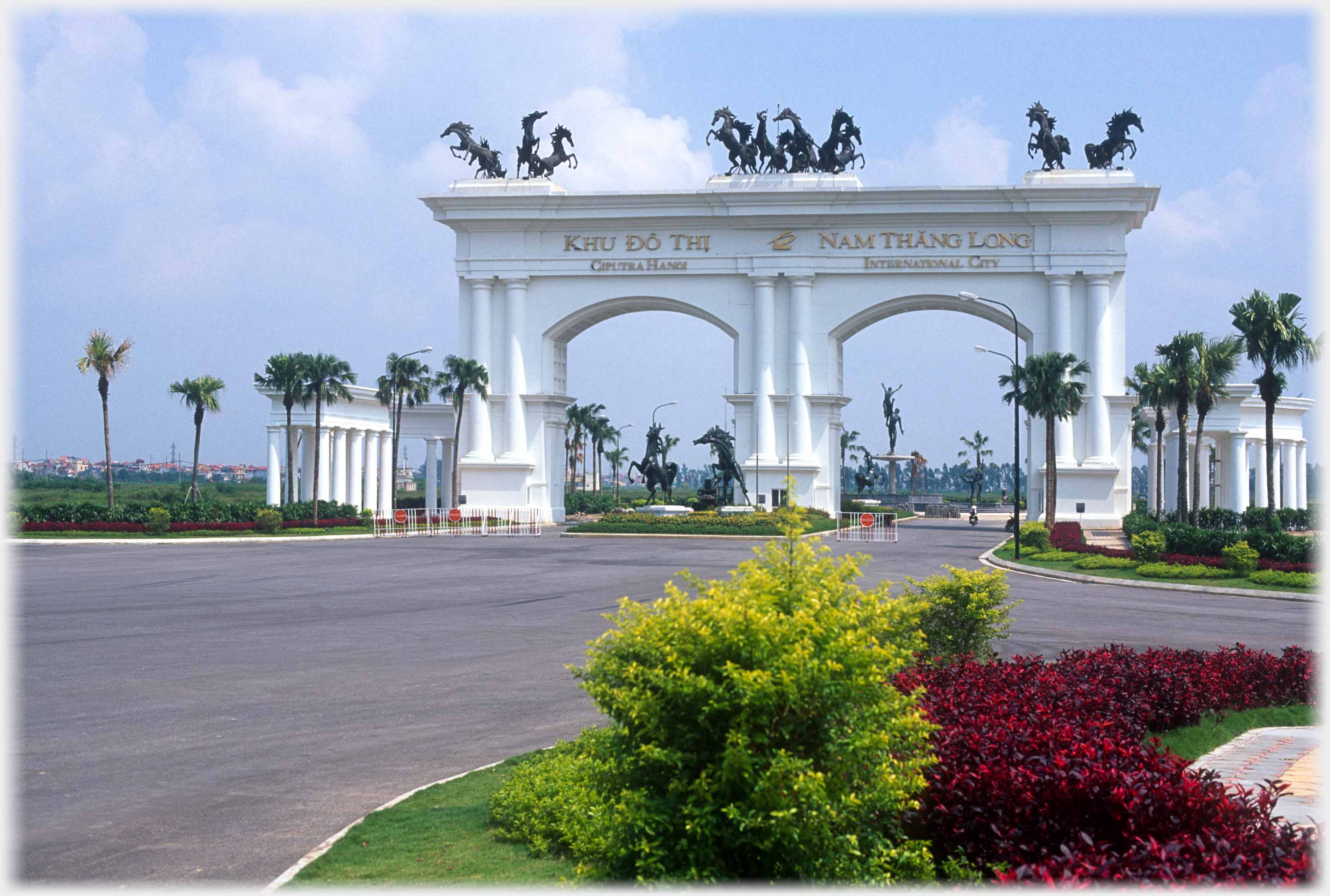 Monumental two arched white gate with horses on top.