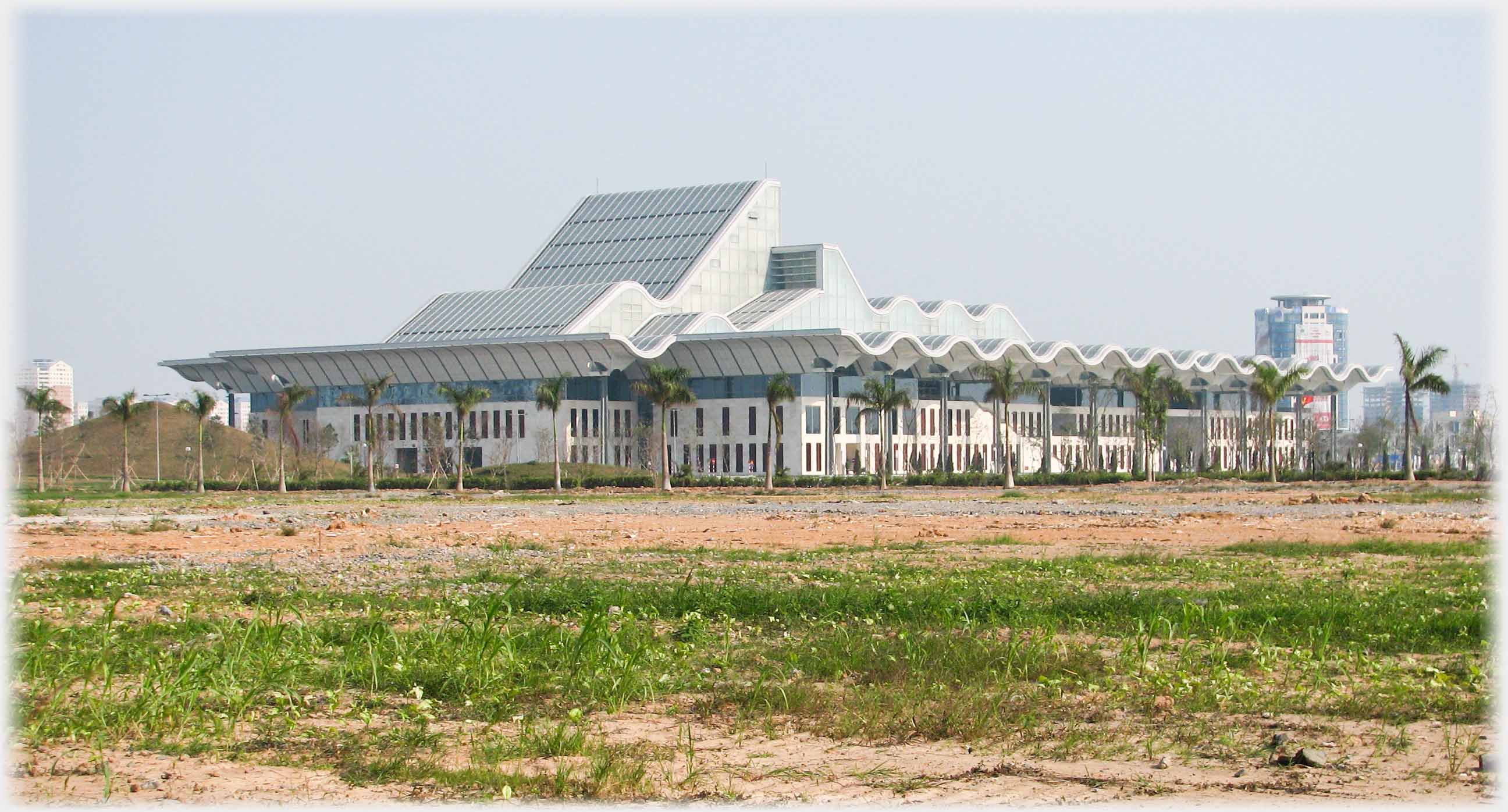 Wavy roof on large low building with sloping higher structure.