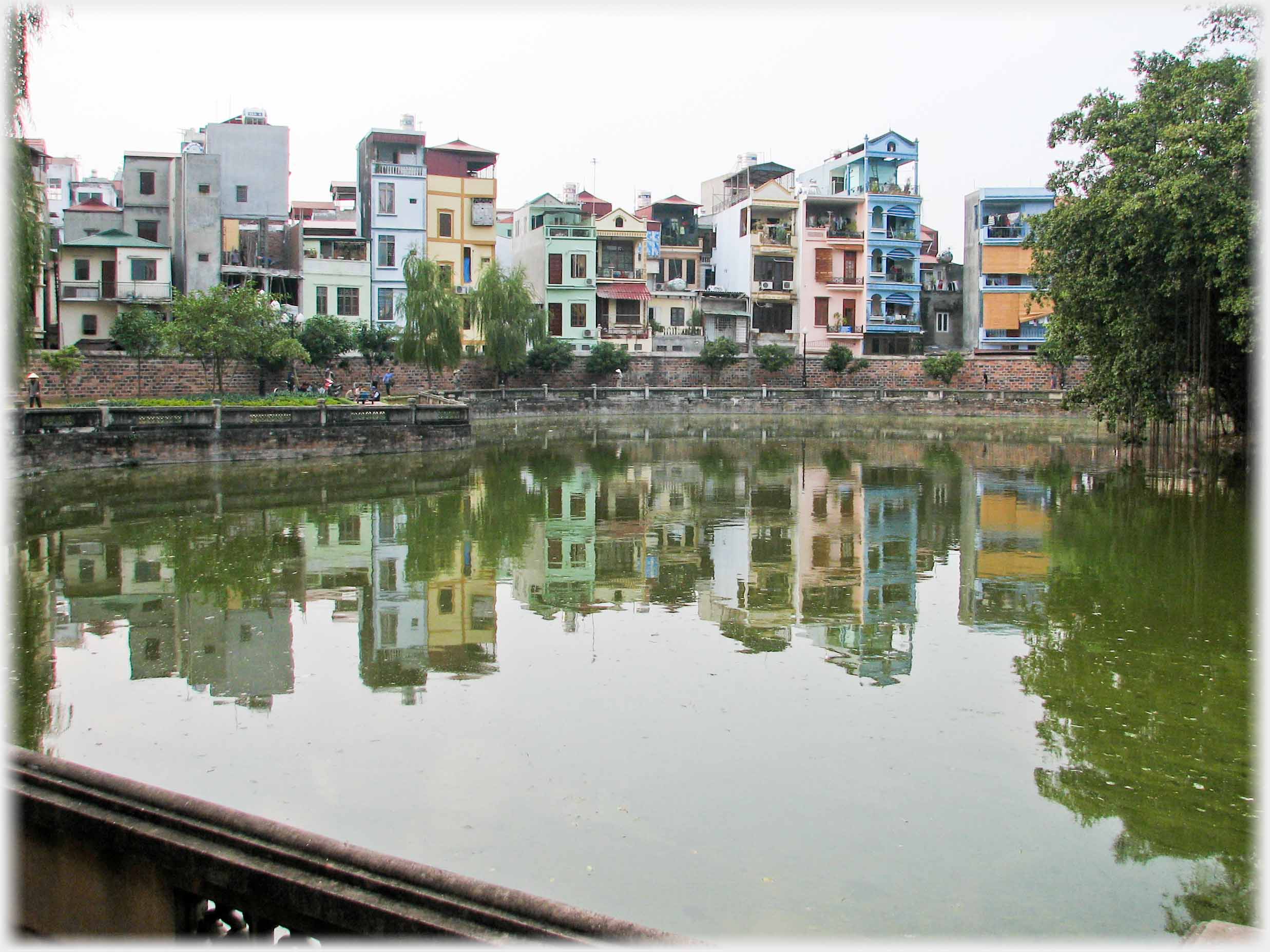 Row of tall narrow houses reflected in water.