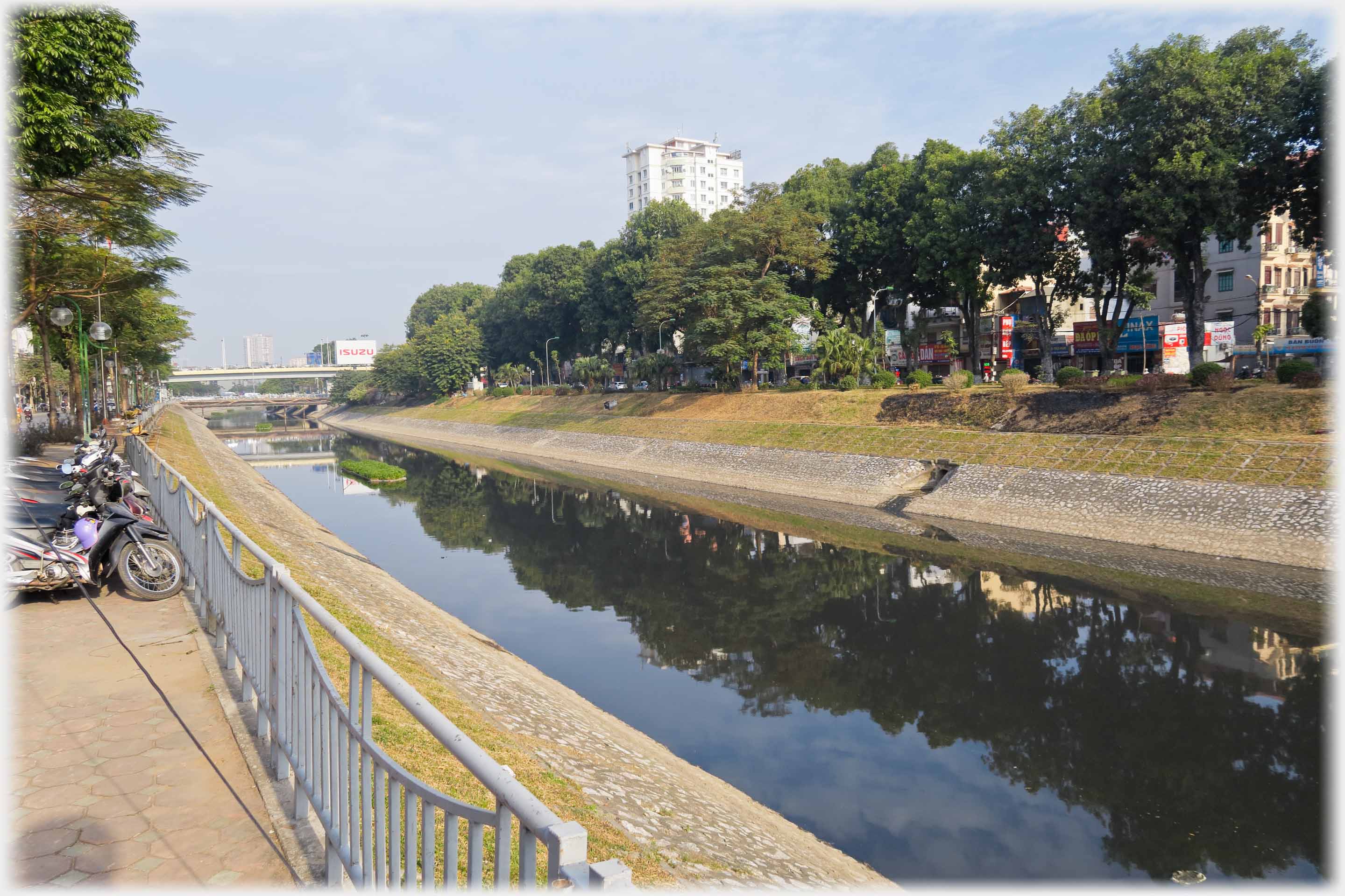 Canalised river with trees and bridge.