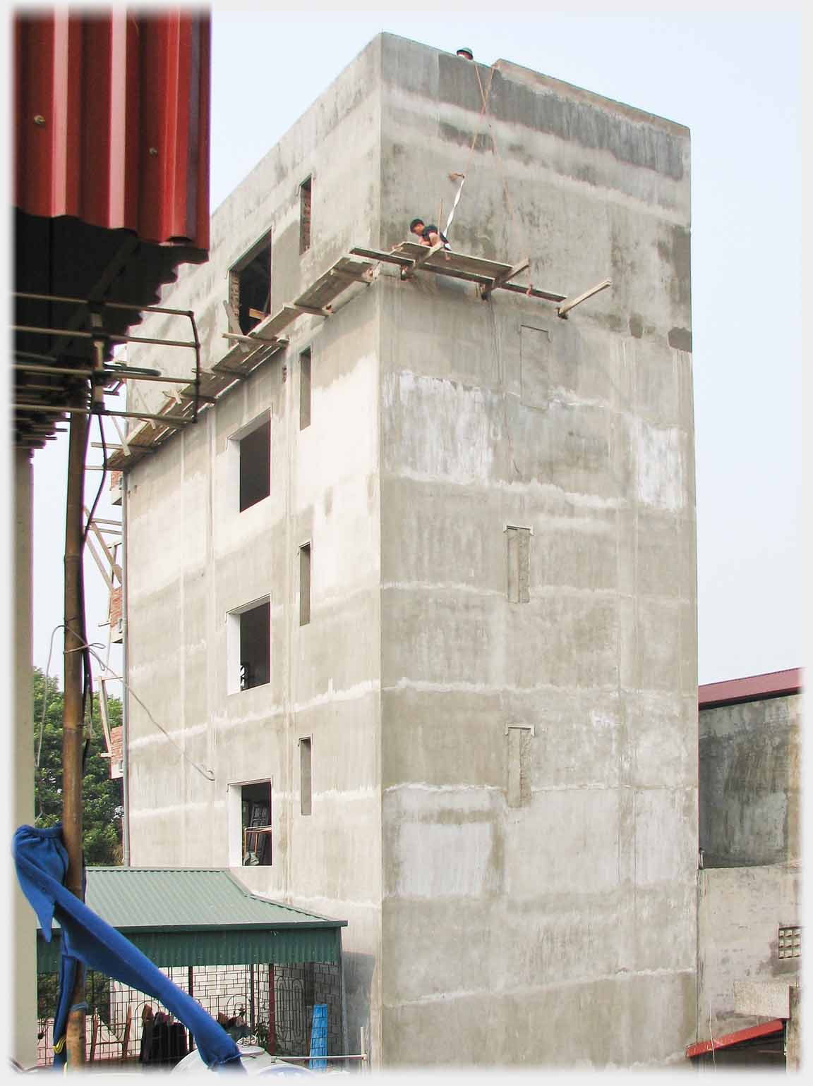 Five story concrete building, two planks wide ledge at top floor with no handrail.