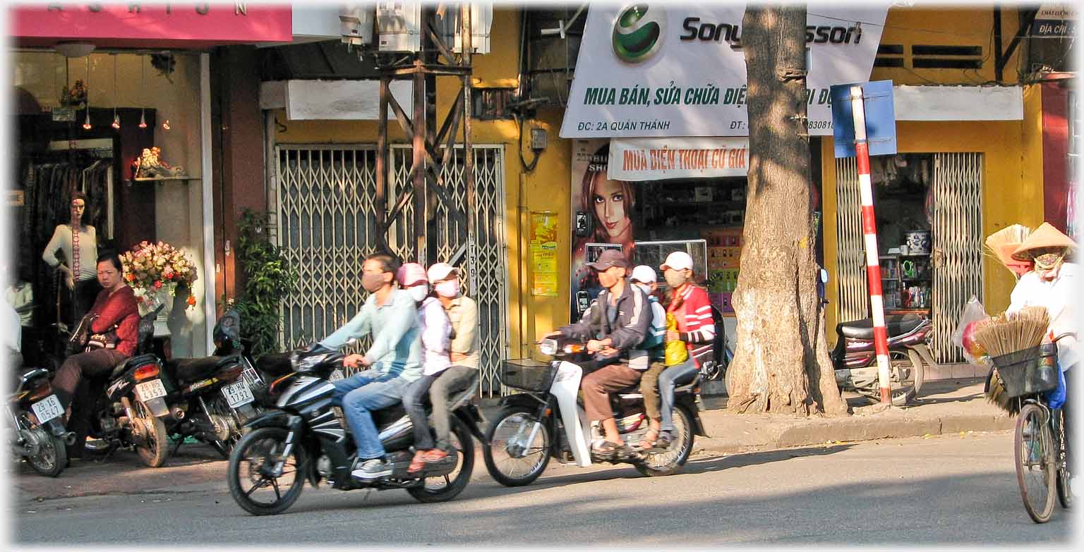 Two motorbikes each with three masked riders, cyclist with mask.