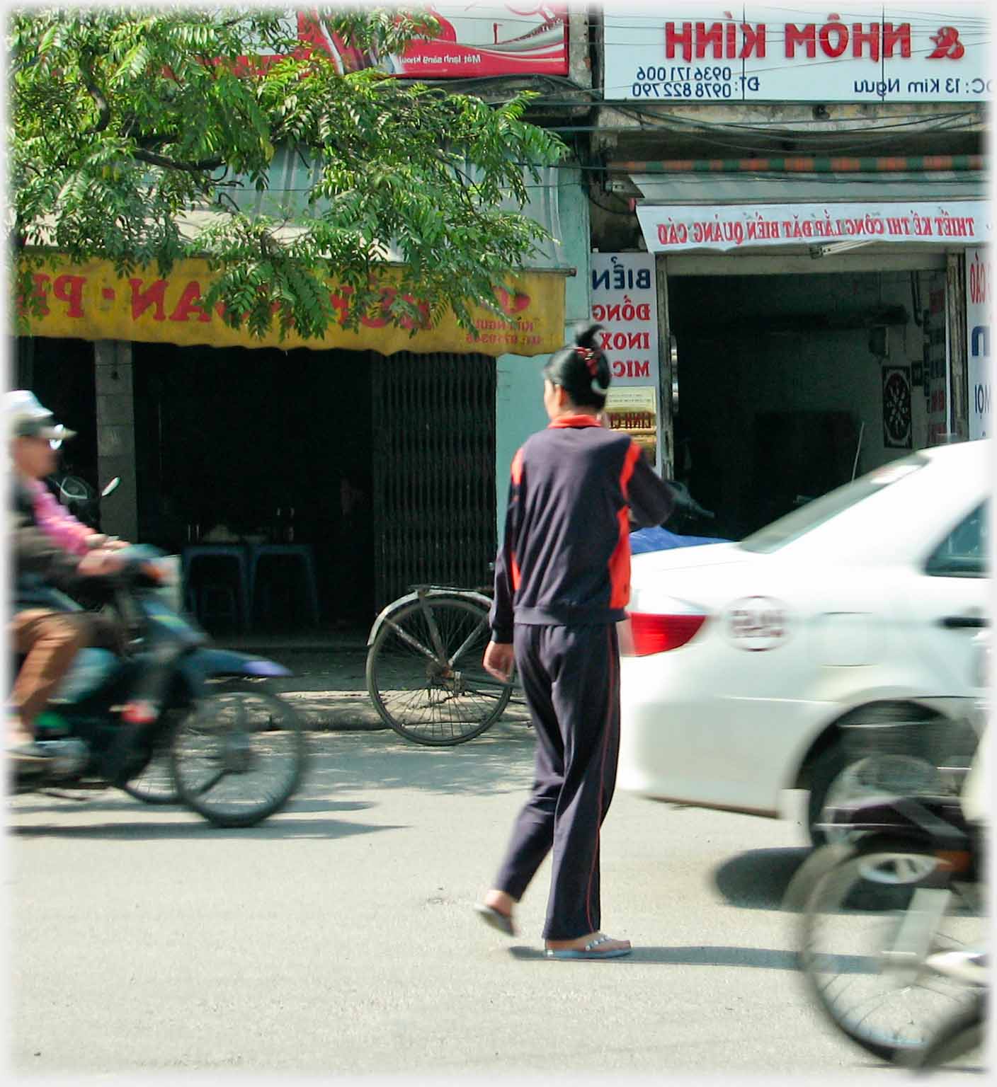 Woman in road with blurred traffic around her.