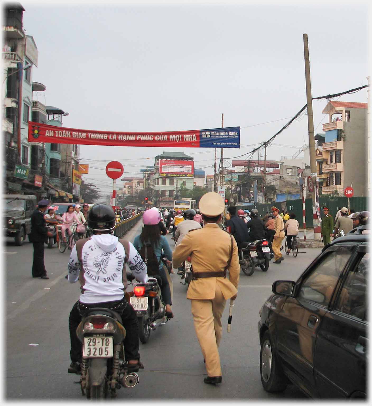 Policeman walking between cars and bikes.