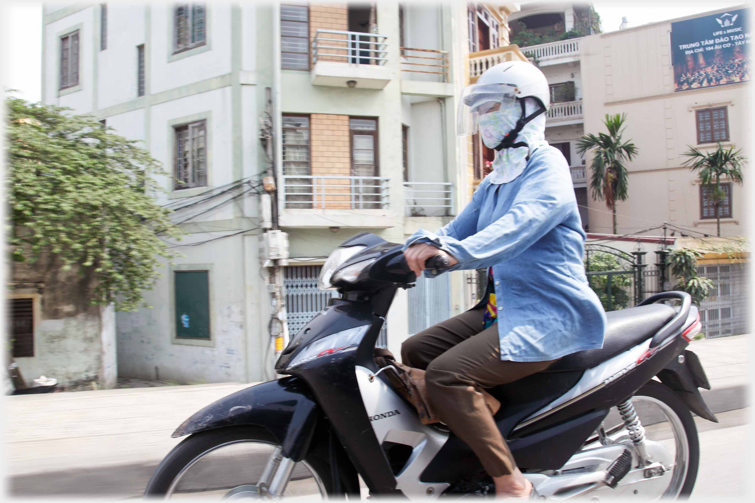 Woman on motorbike with head covering under helmet.